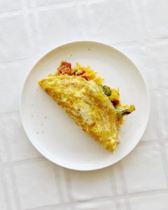 White plate with a folded veggie omelet.