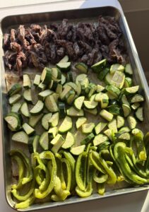 A sheet pan of shredded steak with diced zucchini and curled zucchini ribbons.