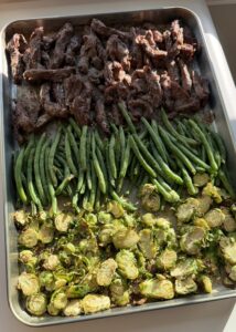 A sheet pan of steak with green beans and Brussels sprouts.