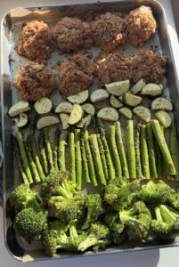 A sheet pan of tuna patties with zucchini, asparagus, and broccoli.